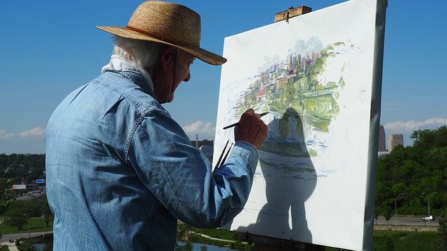Adulto mayor pintando al aire libre.